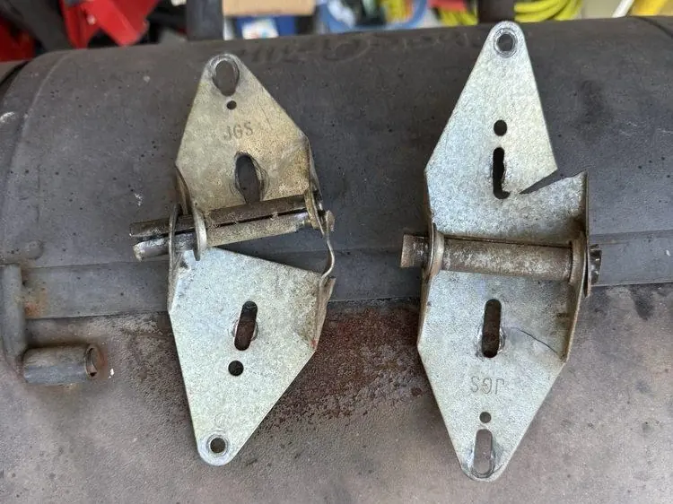 Two garage door hinges, one cracked