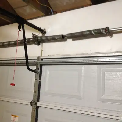 Broken torsion spring above a white garage door