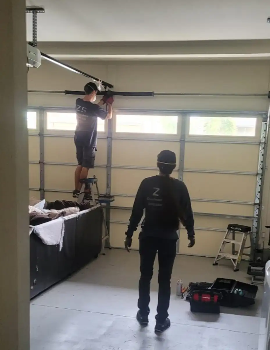 Technicians working on a garage door inside a garage