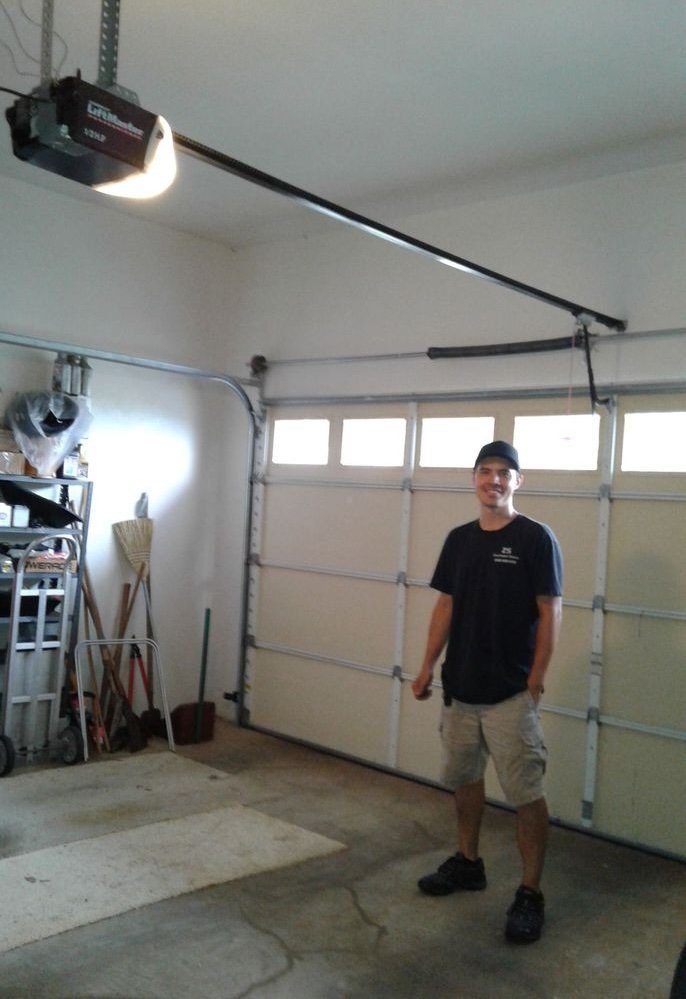 Zach, owner of ZS Overhead Doors, standing in a garage under a garage door opener